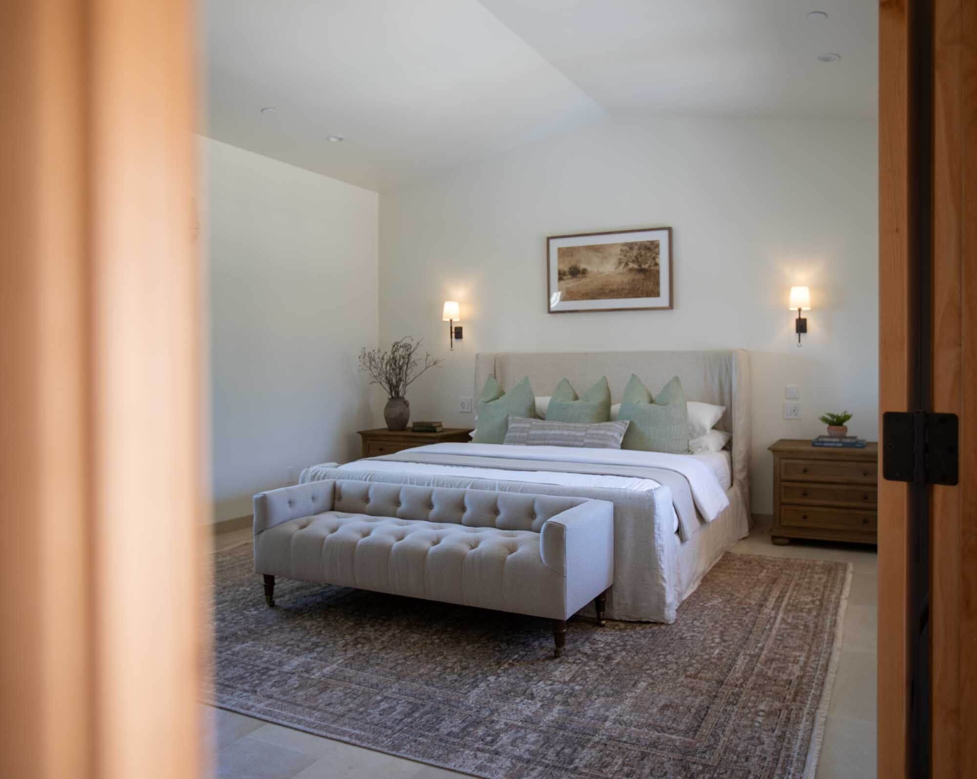 A bedroom with a large bed, a nightstand, a lamp, and a framed picture on the wall.