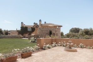 A stone building with a courtyard, a fountain, and a well-maintained lawn.