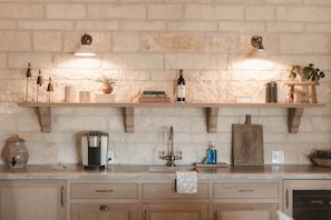 Una cucina con mensole in legno, una macchina da caffè, una bottiglia di vino e una pianta.