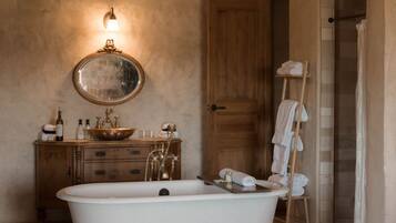 Un baño con una bañera independiente, un tocador de madera, un espejo y un perchero para toallas.