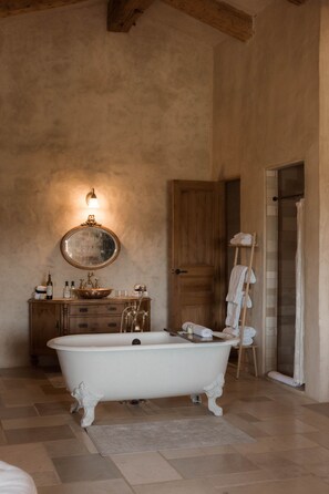 A bathroom with a freestanding bathtub, a wooden vanity, a mirror, and a towel rack.