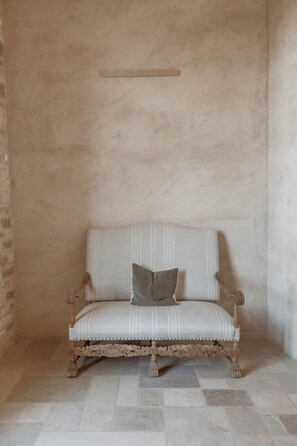 A chair with a cushioned seat and backrest, positioned against a plain wall with a textured surface.