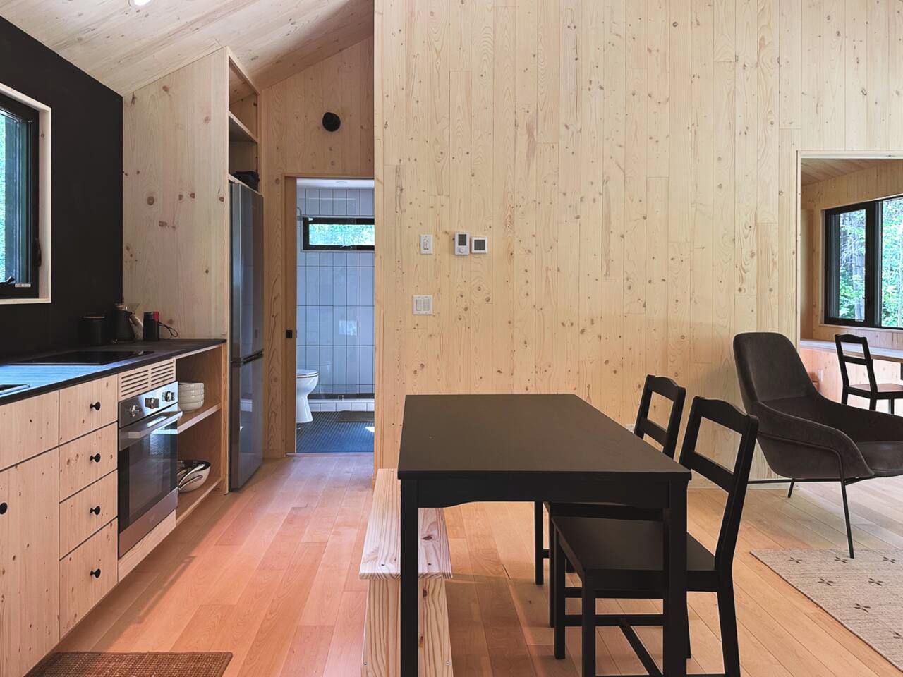 A modern kitchen with wooden cabinetry, a dining table, and chairs.