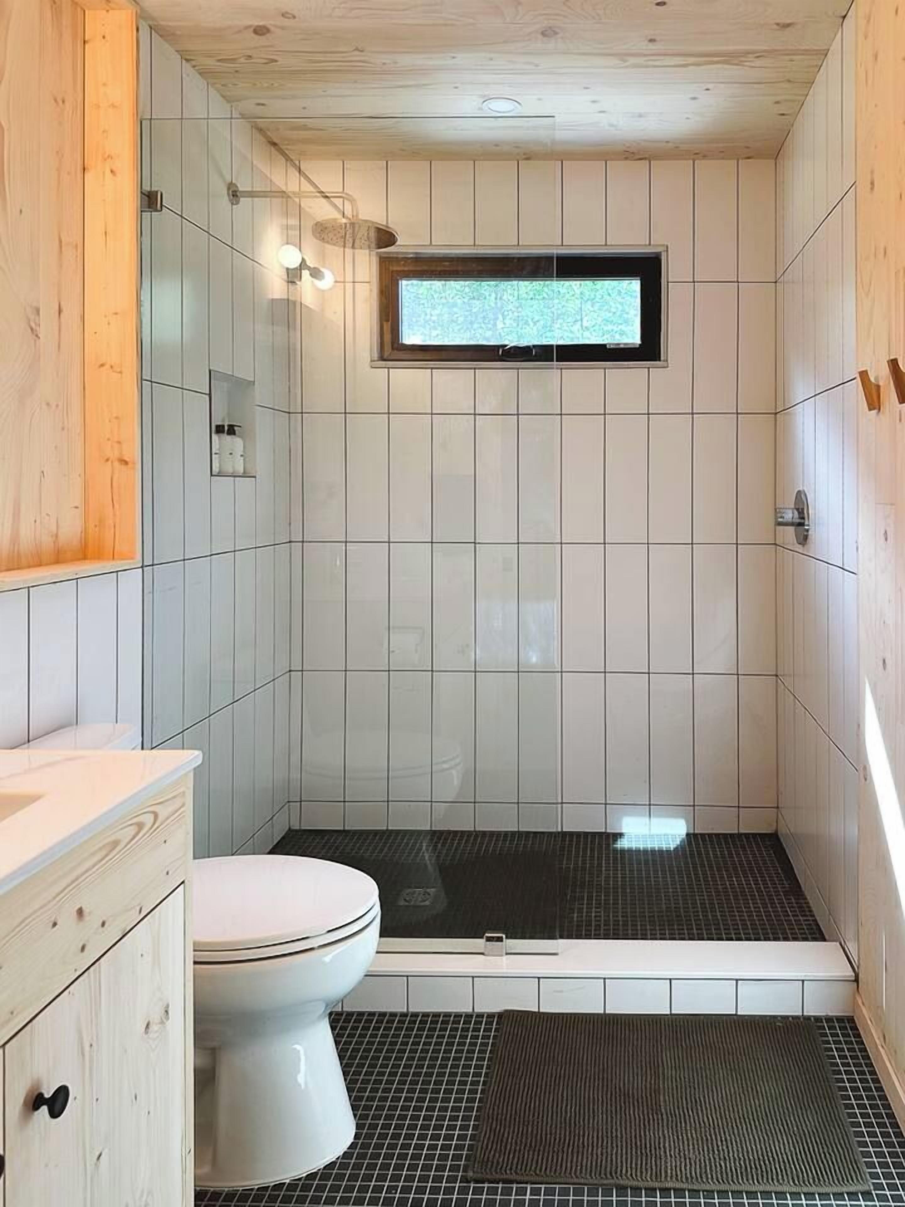 A small bathroom with a toilet, a shower area, and a window.