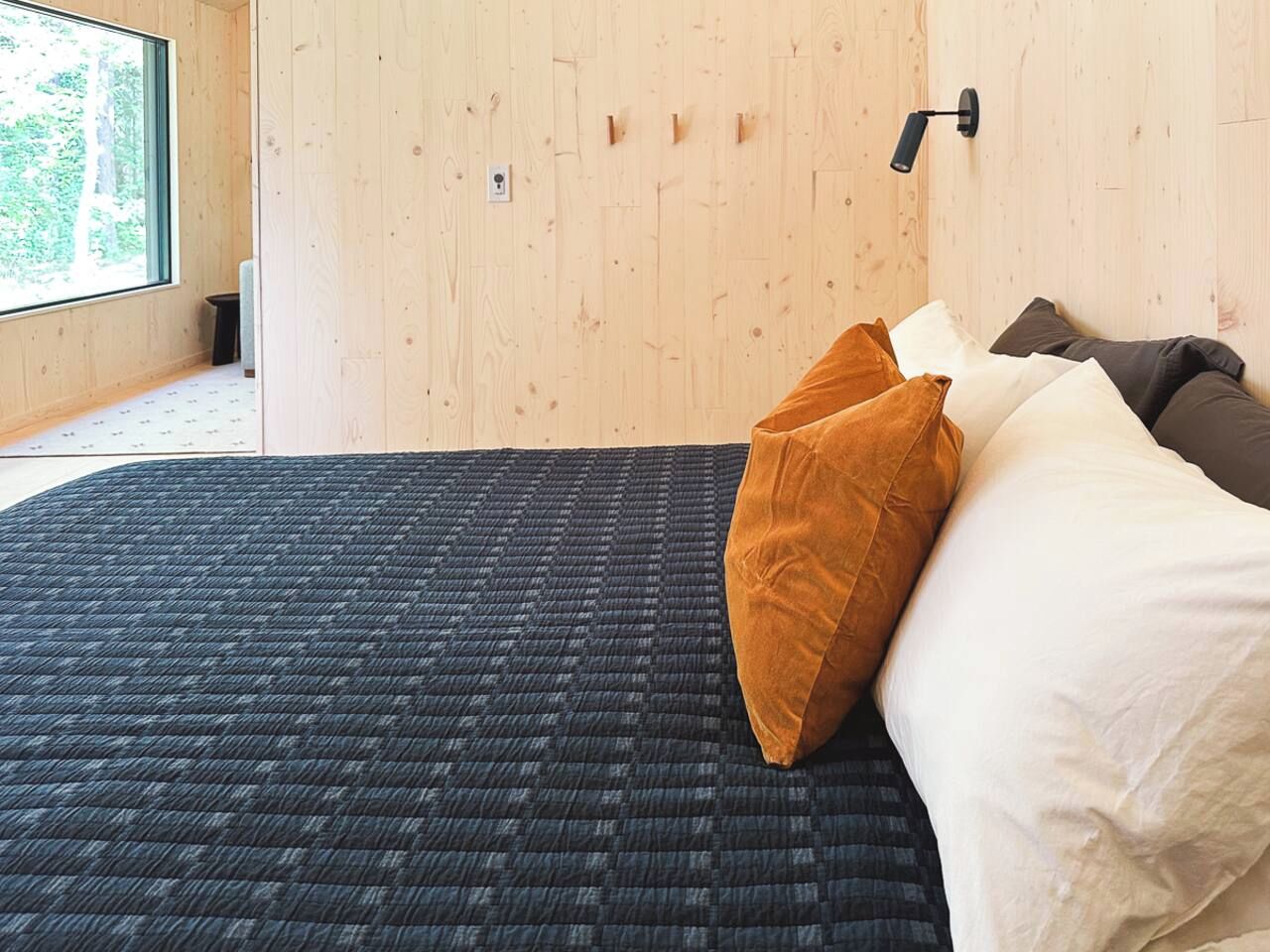 A room with a bed, a window, and a wall-mounted light fixture.