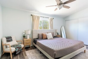 A bedroom with a bed, a chair, a nightstand, a lamp, a window with curtains, and a ceiling fan. - Beyond Horizon, Private Casita, Stargazing & Fast WiFi (Joshua Tree)