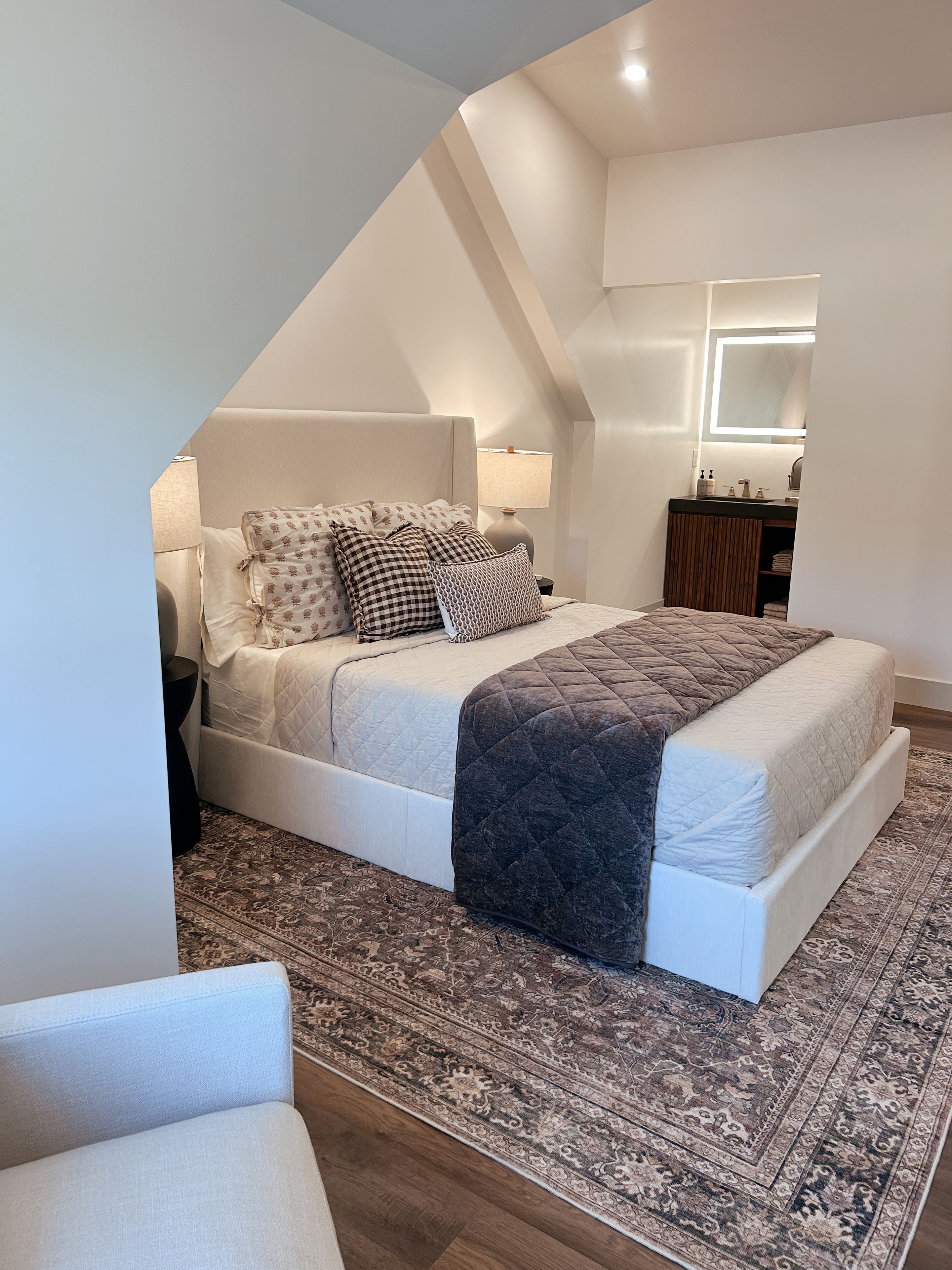 Ein Schlafzimmer mit einem Bett, Nachttischen, einem Spiegel und einem Teppich.
