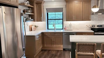 Una cocina moderna con armarios de madera, electrodomésticos de acero inoxidable y un amplio ventanal.
