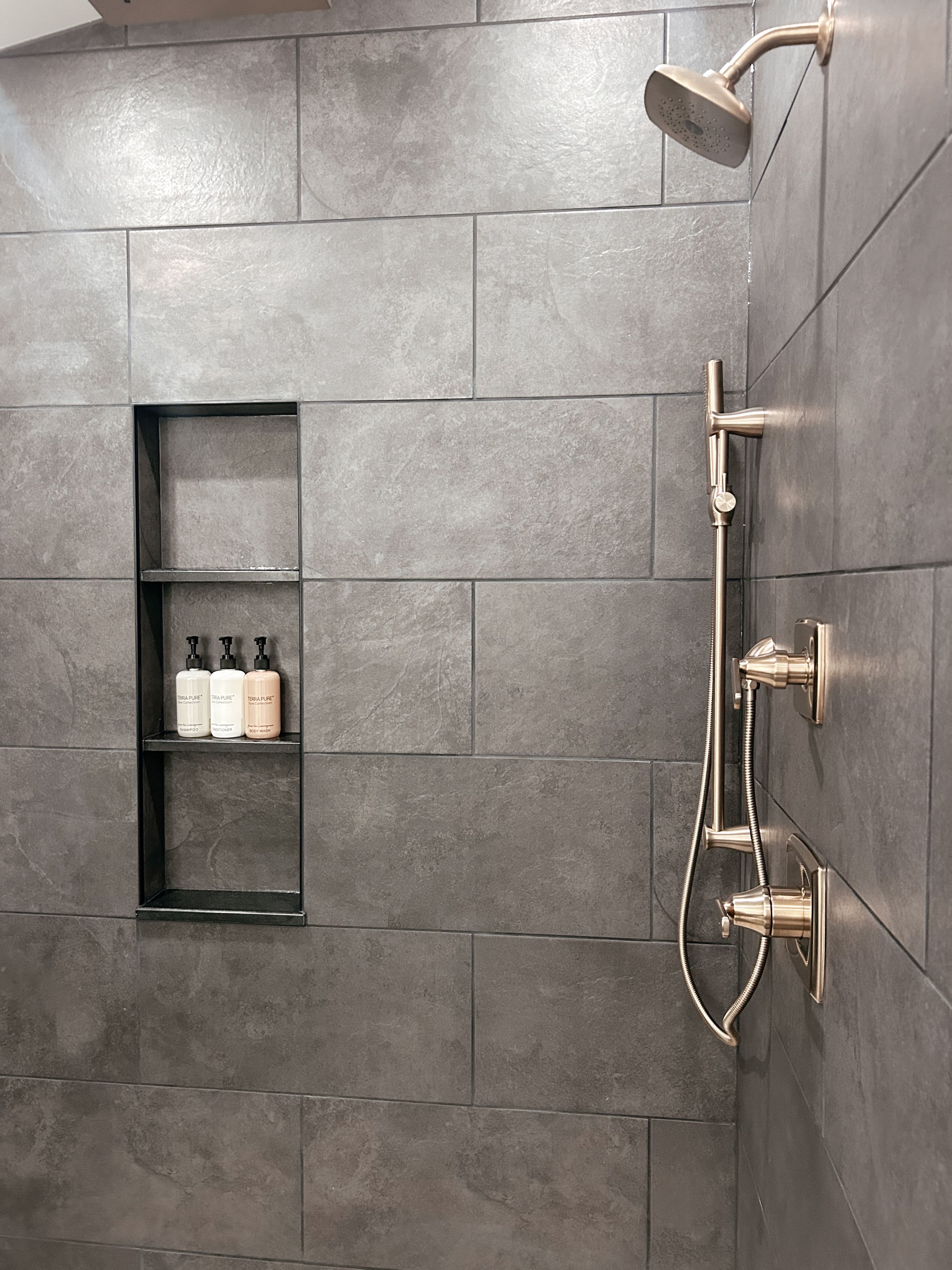 A modern shower area with a wall-mounted showerhead and control knobs.