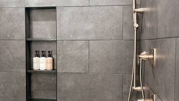 A modern shower area with a wall-mounted showerhead and control knobs.