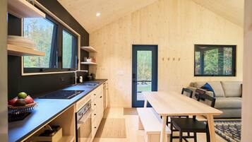 Une cuisine moderne dotée d’une cuisinière intégrée, d’un coin repas avec un banc et d’une vue sur l’extérieur grâce à une porte.