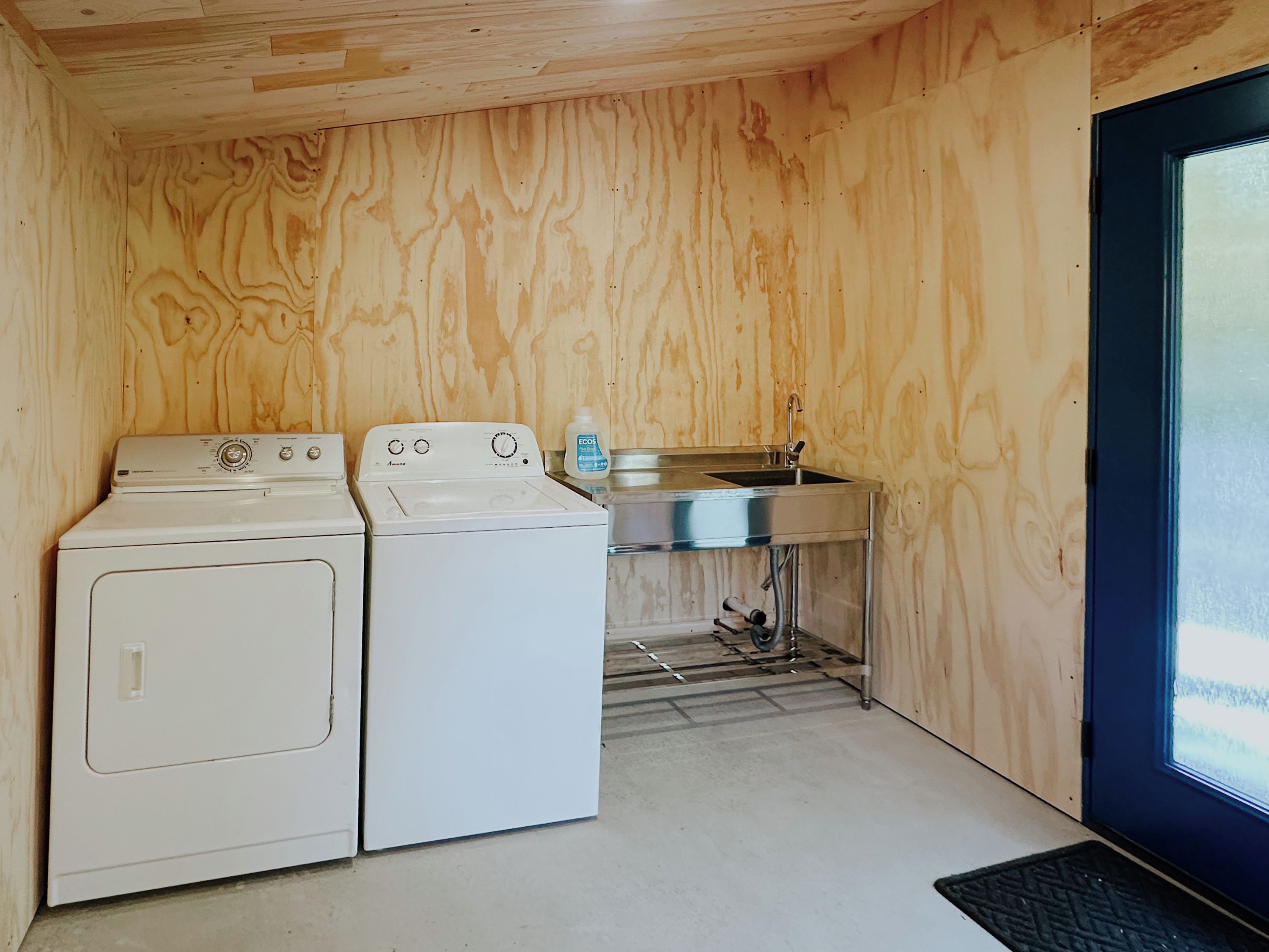 A compact laundry room with two washing machines, a sink, and a window.