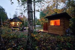 A cabin with a visible interior and exterior, surrounded by trees and foliage. - Scandi Spruce Cabin in the Woods #2 (Grand Rapids)