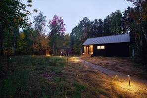 A cabin with a metal roof, surrounded by a forest with autumn foliage. - Scandi Spruce Cabin in the Woods #2 (Grand Rapids)