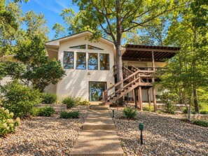 A two-story house with a covered porch and a stone pathway leading to the entrance. - Hot Springs Village Lakefront Escape-Private Dock and Golf (Hot Springs Village)