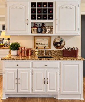 A kitchen with white cabinetry, a granite countertop, a sink, and various kitchen items including a potted plant, a framed picture, and a horse-themed decoration. - Hot Springs Village Lakefront Escape-Private Dock and Golf (Hot Springs Village)