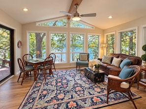 A spacious living room with a large window overlooking a body of water, a ceiling fan, and a patterned rug. - Hot Springs Village Lakefront Escape-Private Dock and Golf (Hot Springs Village)