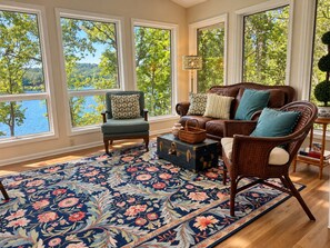 A room with large windows, a sofa, a chair, a rug, and a small table with a lamp. - Hot Springs Village Lakefront Escape-Private Dock and Golf (Hot Springs Village)