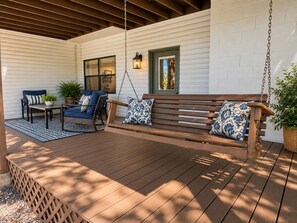 A covered outdoor seating area with a wooden bench and chairs, a hanging swing, and a potted plant. - Hot Springs Village Lakefront Escape-Private Dock and Golf (Hot Springs Village)