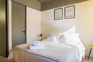 Ein Hotelzimmer mit einem Bett, einer Tür und zwei gerahmten Bildern an der Wand.