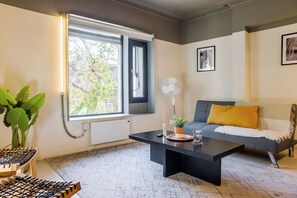 Ein modernes Wohnzimmer mit einer Couch, einem Couchtisch und einem großen Fenster.