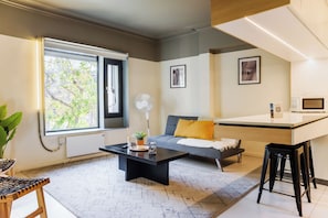 Ein stilvoller Wohnraum mit Sofa, Couchtisch, einer kleinen Küchenzeile und einem Esstisch.