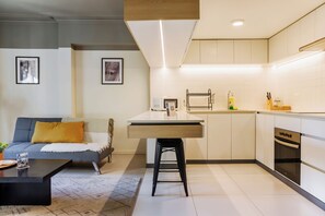 Eine moderne Küche mit Kochinsel, ein Essbereich mit einer Couch und ein Wohnzimmer mit Couchtisch.