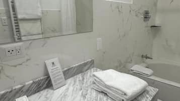 A bathroom with a marble sink, a mirror, a towel rack, and a shower area.