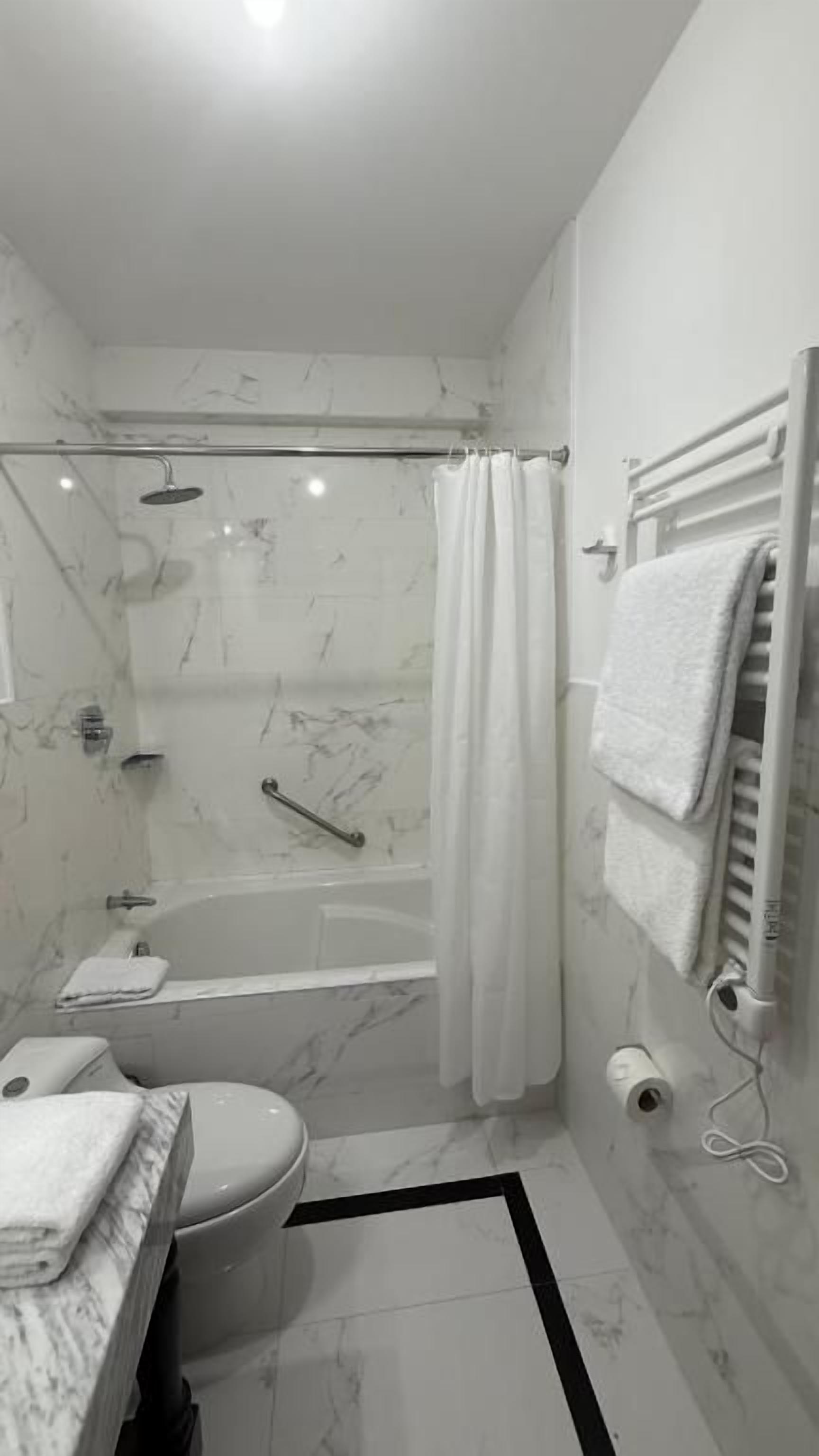 A modern bathroom with a bathtub, toilet, and shower area.