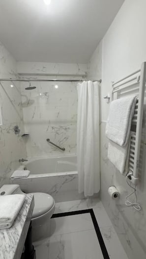 Um banheiro moderno com banheira, vaso sanitário e área de chuveiro.