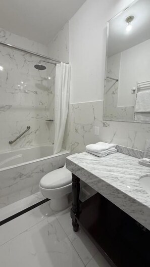 A modern bathroom with a shower, toilet, and a marble vanity.