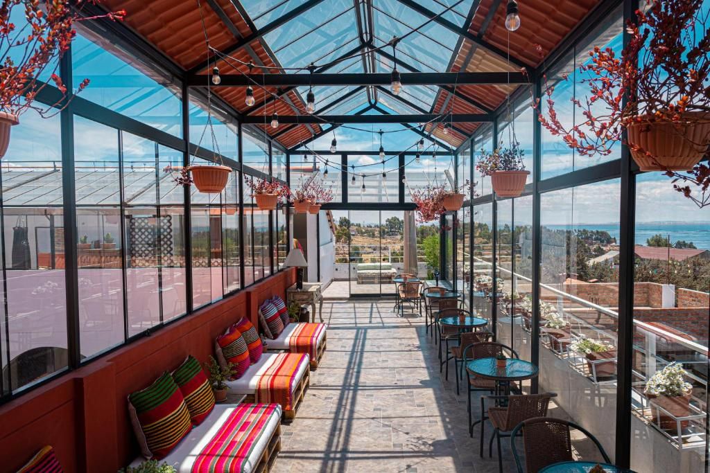 A covered outdoor seating area with tables and chairs, a bench with colorful cushions, and hanging plants.