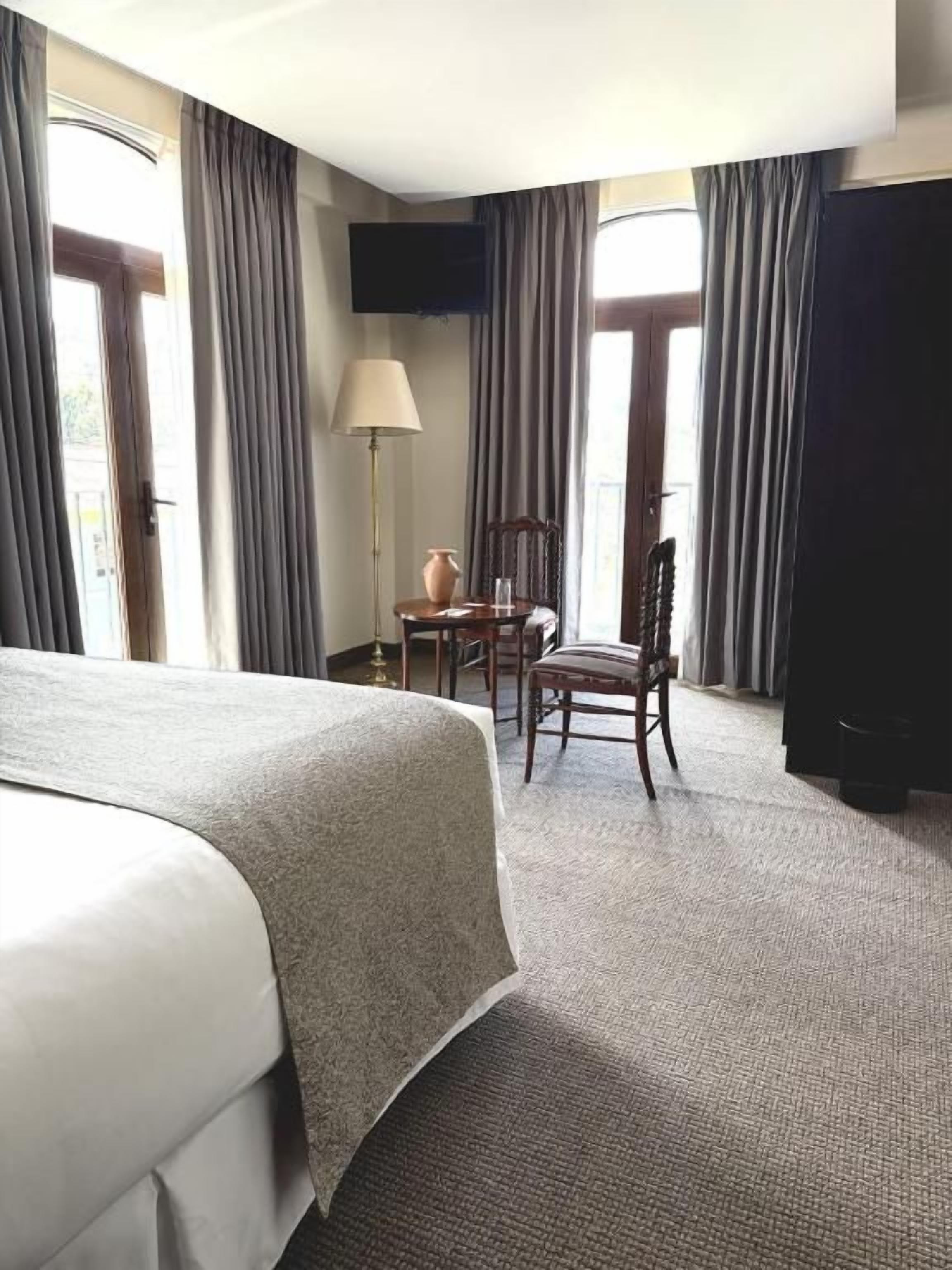 A hotel room with a large bed, a desk, a chair, and a television.