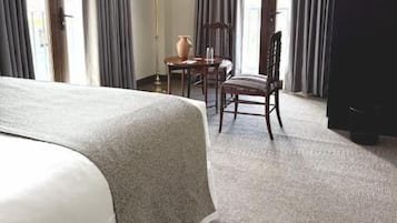 A hotel room with a large bed, a desk, a chair, and a television.