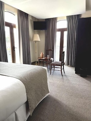 Una habitación de hotel con una cama grande, un escritorio, una silla y un televisor.