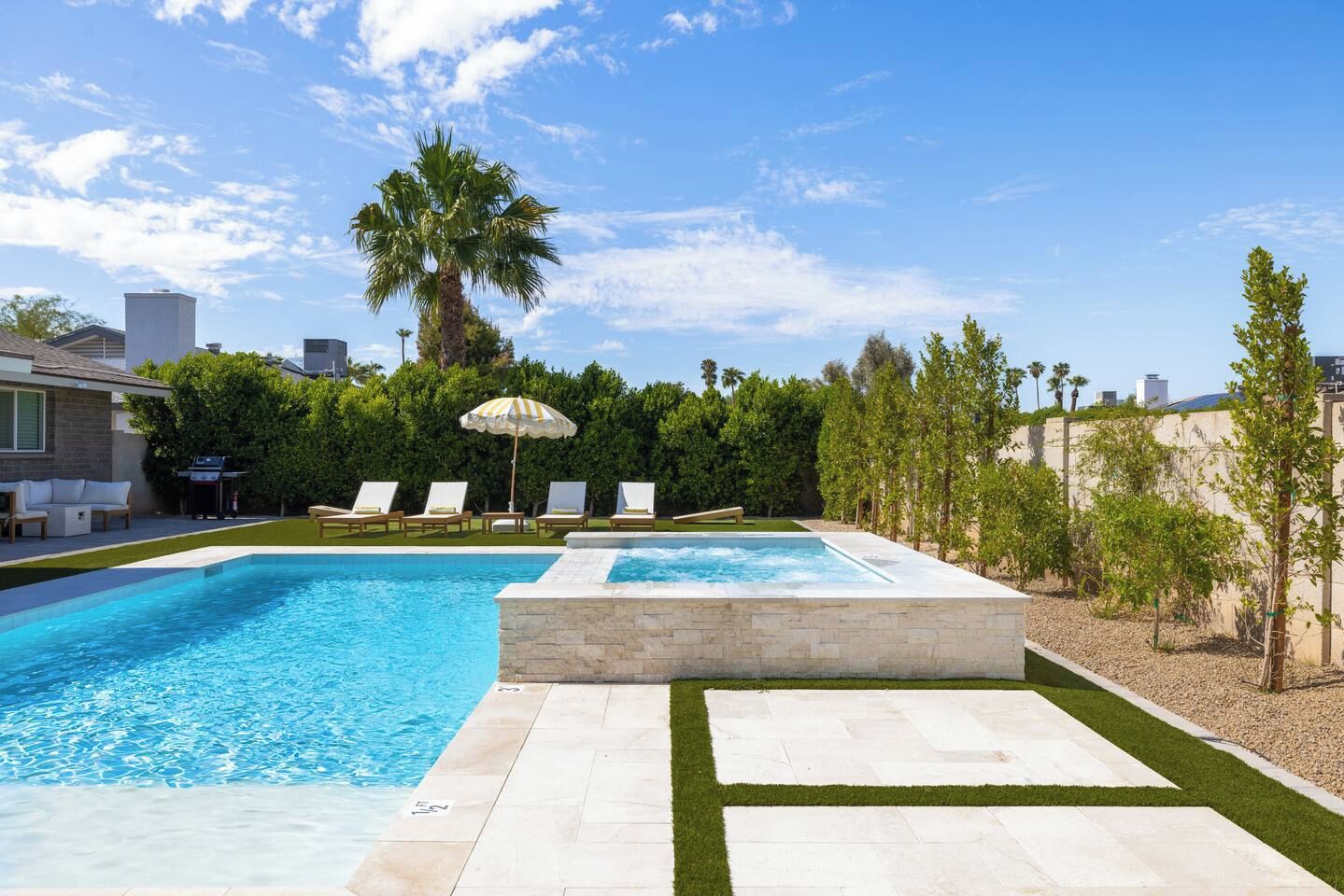 A swimming pool with lounge chairs and a palm tree, surrounded by a landscaped garden.