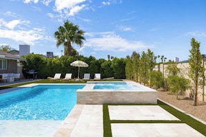 A swimming pool with lounge chairs and a palm tree, surrounded by a landscaped garden. - Terra Aura: Tempe Home with Pool & Spa (Tempe)