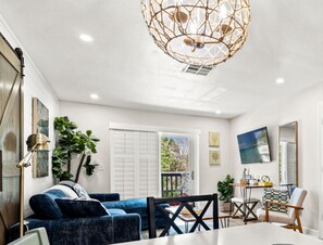 Uma sala de estar moderna com um sofá azul, uma mesa de jantar e um candelabro.