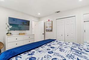 Quarto com uma cama, penteadeira, quadro e porta.