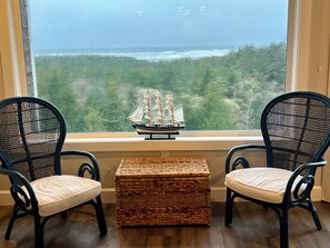 Two wicker chairs with cushions, a small woven table, and a model ship on a windowsill. - Sea La Vie- Luxury Ocean View Condo- 1 to 6 month stay (Seaview)