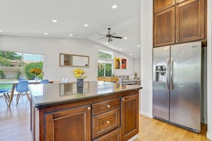 Kitchen with a large stainless refrigerator and an island that opens to the breakfast nook - Pool, Spa & Games  4BR Near Indio Polo Grounds (Indio)