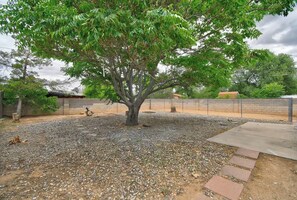 A tree in a gravel area with a brick wall and a concrete path. - Spacious 4-bedroom cozy cottage (Albuquerque)