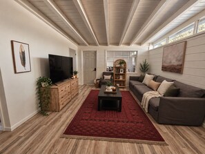 A living room with a television, sofa, coffee table, and a red patterned rug. - Spacious 4-bedroom cozy cottage (Albuquerque)