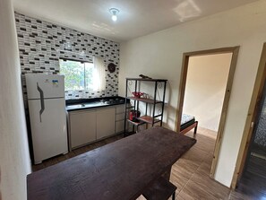 A compact kitchen with a refrigerator, stove, and a wooden table. - House for 6 People - Recanto dos Eucaliptos - Great location - Pet Friendly (Imbituba)