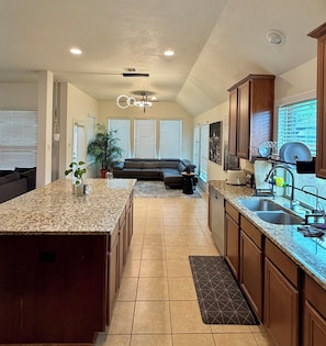 A kitchen with granite countertops, a built-in oven, and a dining area with a sofa. - Spacious, bright & modern 3BR+ office in a very safe neighborhood with lakes. (Houston)