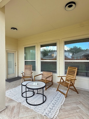 A covered patio area with a table and four wooden chairs, a patterned rug, and large windows with blinds. - Spacious, bright & modern 3BR+ office in a very safe neighborhood with lakes. (Houston)