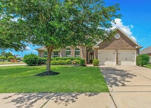 A two-story house with a brick exterior, a front yard with a tree, and a garage. - Spacious, bright & modern 3BR+ office in a very safe neighborhood with lakes. (Houston)