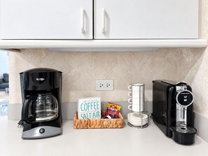 Eine Küchenarbeitsplatte mit einer Kaffeemaschine, einem Schild mit der Aufschrift 'Coffee and the smell of Salt Air', einer Packung Folgers Kaffee und einem Wasserspender.