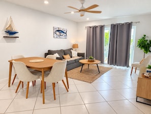 A modern living room with a dining area, a sofa, a coffee table, and a ceiling fan. - Marathon Key Getaway (Marathon)