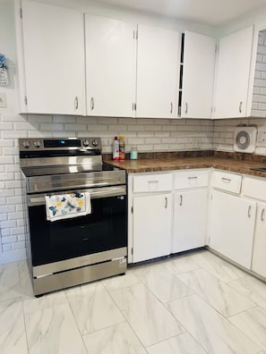 A kitchen with white cabinets, a stainless steel oven, and a granite countertop. - Peaceful 2-bedroom house in charming Rutland! Have fun with family & friends (Rutland)